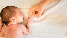 a baby laying on its back with it's hand touching the finger of an adult