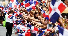 a group of people holding flags and waving at the camera while walking down a street