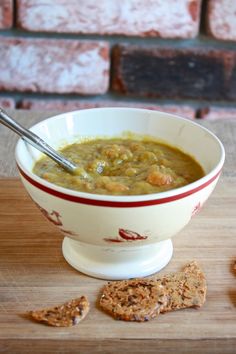 a white bowl filled with soup next to crackers on top of a wooden table