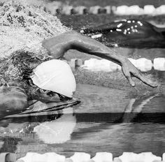 a man swimming in a pool with his head above the water while wearing a helmet