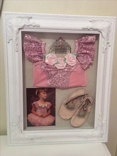 a baby's pink outfit and shoes in a white frame