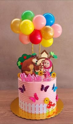 a birthday cake decorated with balloons and an image of a cartoon character on the top