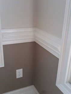 the corner of a room with a window and white trim on the walls is empty