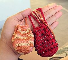 two small crocheted purses being held in someone's hand