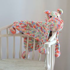 a crocheted teddy bear sitting on top of a white rocking chair