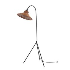 a floor lamp with a wooden shade on it's head and black metal legs