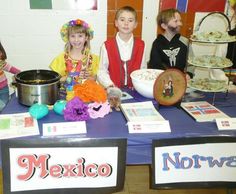 three children are sitting at a table with mexican themed items on it and there is a sign that says, mexico