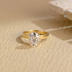 a yellow gold engagement ring with a single diamond on the side, sitting on top of a piece of paper