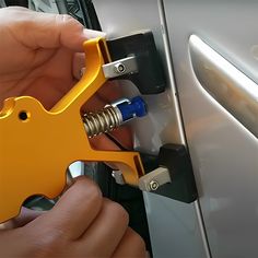 a person is opening the door handle on a car with an orange tool attached to it