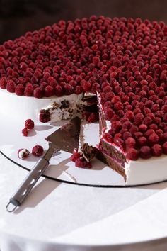 a cake with raspberries on it and a slice missing