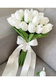 a bouquet of white tulips tied to a couch with a ribbon around it