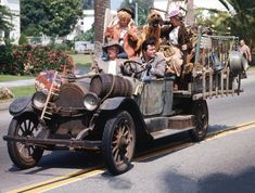 an old fashioned car with people riding in the back