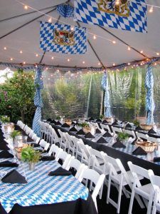 tables and chairs are set up under a tent for an outdoor event with blue and white checkered tablecloths