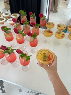 a table topped with lots of glasses filled with different types of drinks and desserts