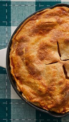 an apple pie is shown in a cast iron skillet on a checkered table cloth