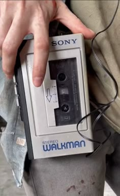 a person holding an electronic device in their left hand, with the word walkman written on it