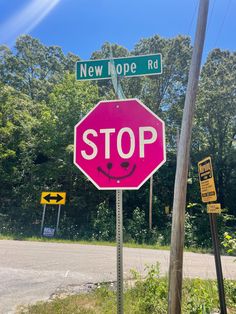 a stop sign with a smiley face painted on the side of it and two street signs above it