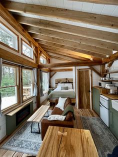 the interior of a tiny cabin with wood flooring and exposed ceilings, windows, and furniture