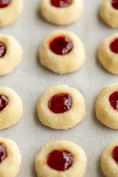 small cookies with jam on them sitting on a baking sheet