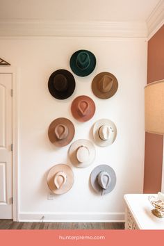 several hats are mounted on the wall above a white dresser and table in a room