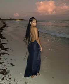 a woman standing on top of a beach next to the ocean