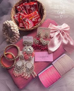 various jewelry and candy items on a pink cloth next to a basket filled with candy