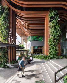 people are walking around in an open area with plants on the walls and wooden columns