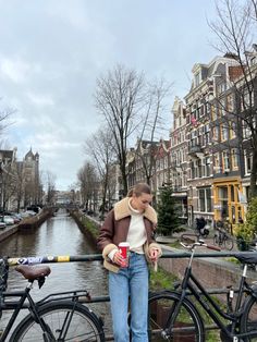 a woman standing next to a river with bicycles