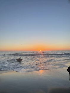 a person riding a surfboard on top of a wave in the ocean at sunset