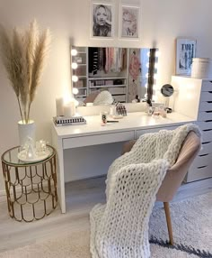 a white desk topped with a mirror next to a chair covered in a fluffy blanket