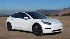 a white tesla model 3 parked in the desert