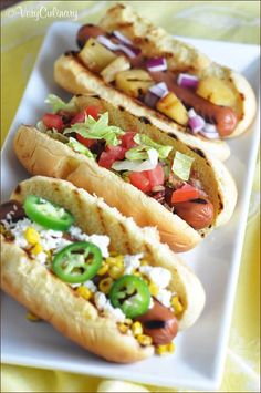 three hot dogs with toppings on a white plate