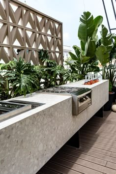 an outdoor kitchen with stainless steel appliances and potted plants on the roof terrace area