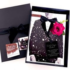 a black box with a pink rose in it next to a card and some other items