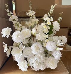 a bouquet of white flowers sitting on top of a cardboard box in front of boxes