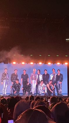 a group of people standing on top of a stage in front of a large screen