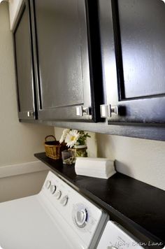 a white washer sitting next to a dryer in a room with black cabinets