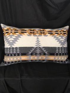 a black and white pillow with an orange design on the front, sitting against a black background