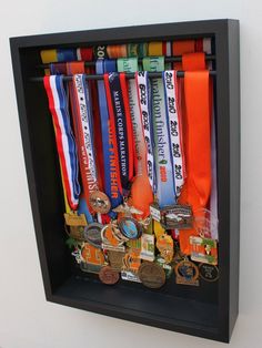 a shadow box with medals hanging from it's sides in front of a white wall