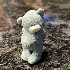 a small blue teddy bear sitting on top of a granite counter next to a fire hydrant