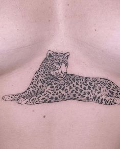 a woman's chest with a tattoo of a cheetah laying on it