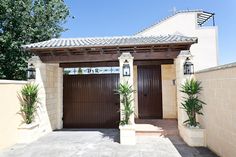 a house with two brown garage doors in front of it and plants on the side