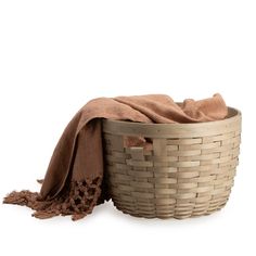 a woven basket with a blanket on top and a brown cloth in the corner next to it