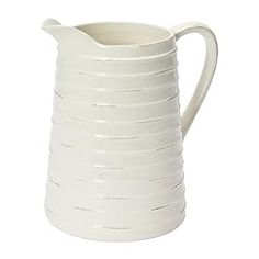 a white ceramic pitcher with wavy lines on the bottom and sides, set against a white background