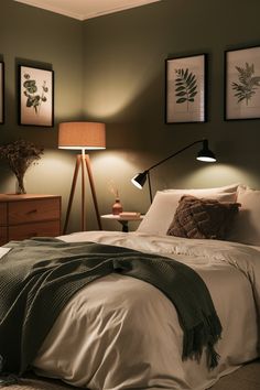 a bedroom with green walls and pictures on the wall above the bed, along with two lamps