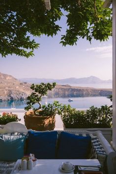 an outdoor seating area with potted plants on the table and water in the background