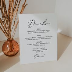 there is a menu card on the table next to a vase with dry grass in it