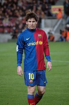 a man standing on top of a soccer field wearing a blue and red uniform with the number 10 on it