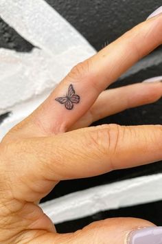 a woman's hand with a small butterfly tattoo on her left thumb and finger