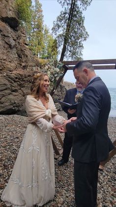 a man and woman standing next to each other on a rocky beach